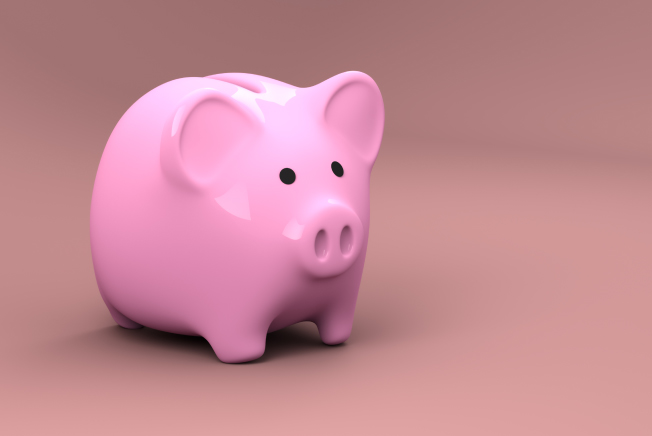 Pink plastic piggy bank used for storing and saving money sits against a darker pink background