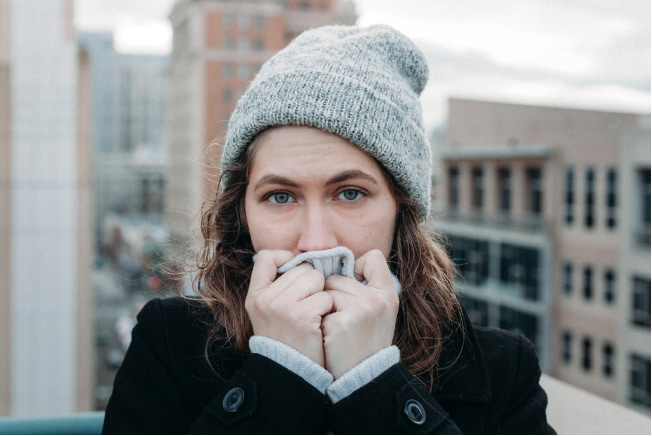 girl dressed for the cold covering her mouth with a glove to protect sensitive teeth