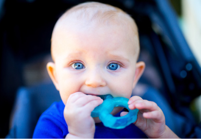 blue eyed baby boy teething on a blue toy