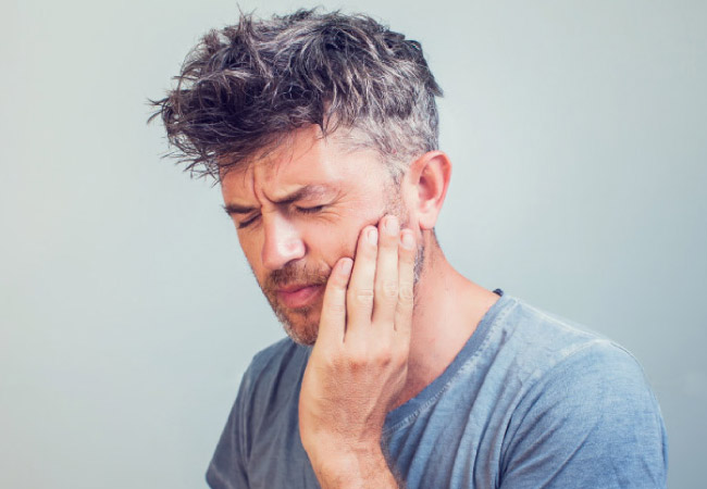 man holding his jaw in pain needing root canal therapy