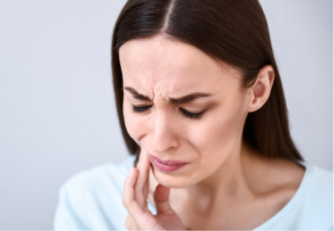 woman holding her jaw in pain from TMJ disorder