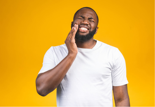 man holds his cheek in pain from canker sores