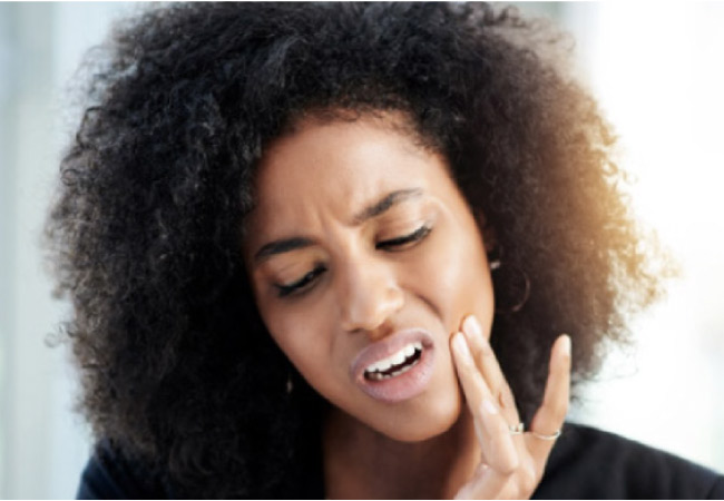 woman holds her jaw in pain with an early sign of dental trouble