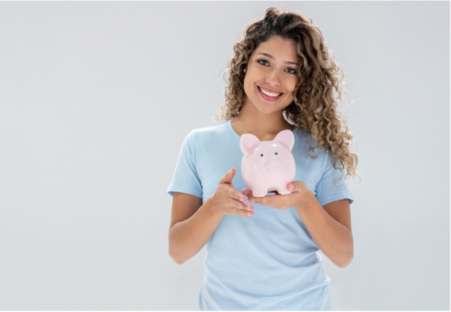 young woman smiles and holds a piggybank after saving money at the dentist