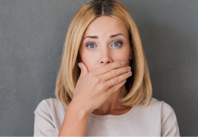 woman covers her mouth with her hand to hide gum disease