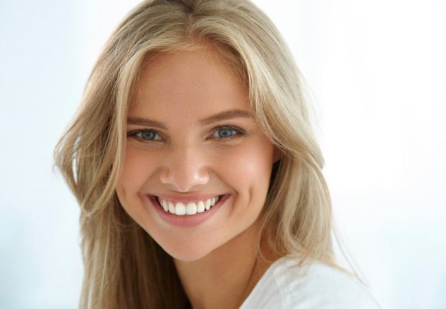 young blond woman flashes a big white smile