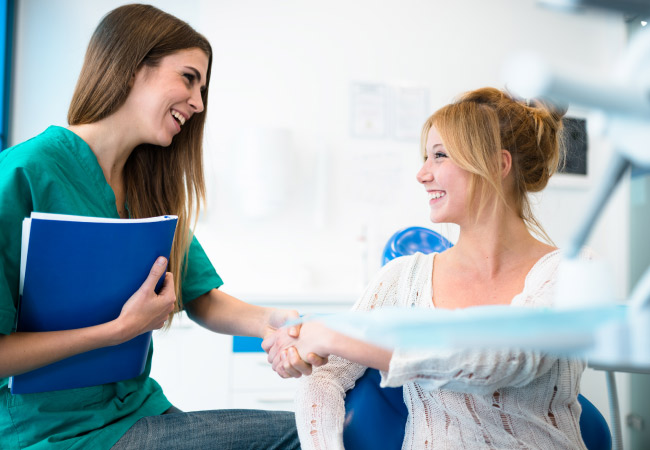 young woman discusses her dental benefits with a dental assistant