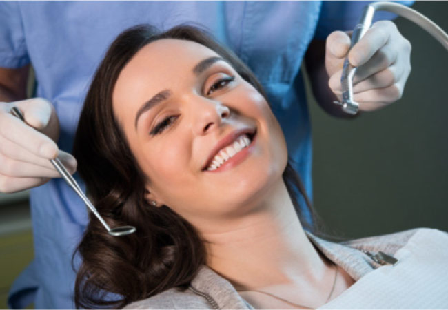 young woman sits in the dentist chair getting a routine cleaning and exam