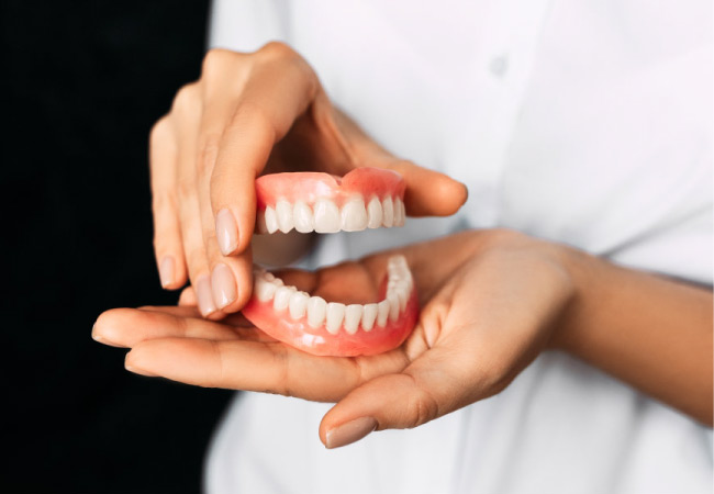 set of dentures held by two hands