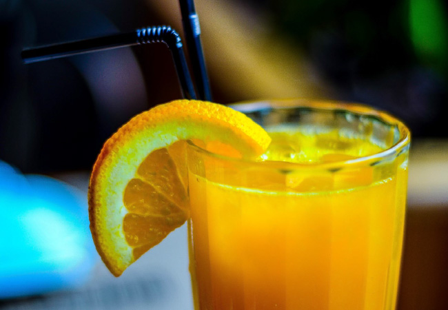 glass of orange juice with an orange wedge on the rim of the glass