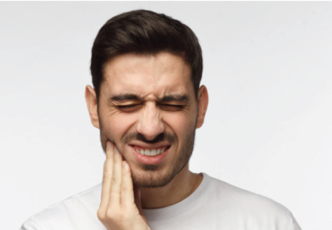 man holds his jaw and grimaces with tooth pain