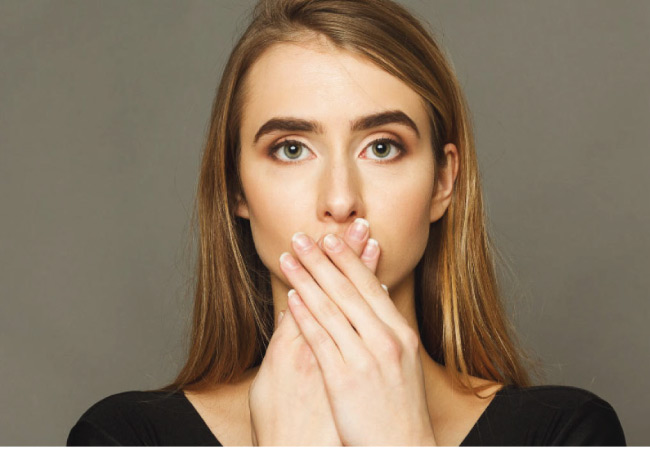 young woman covers her mouth after telling a little lie to the dentist